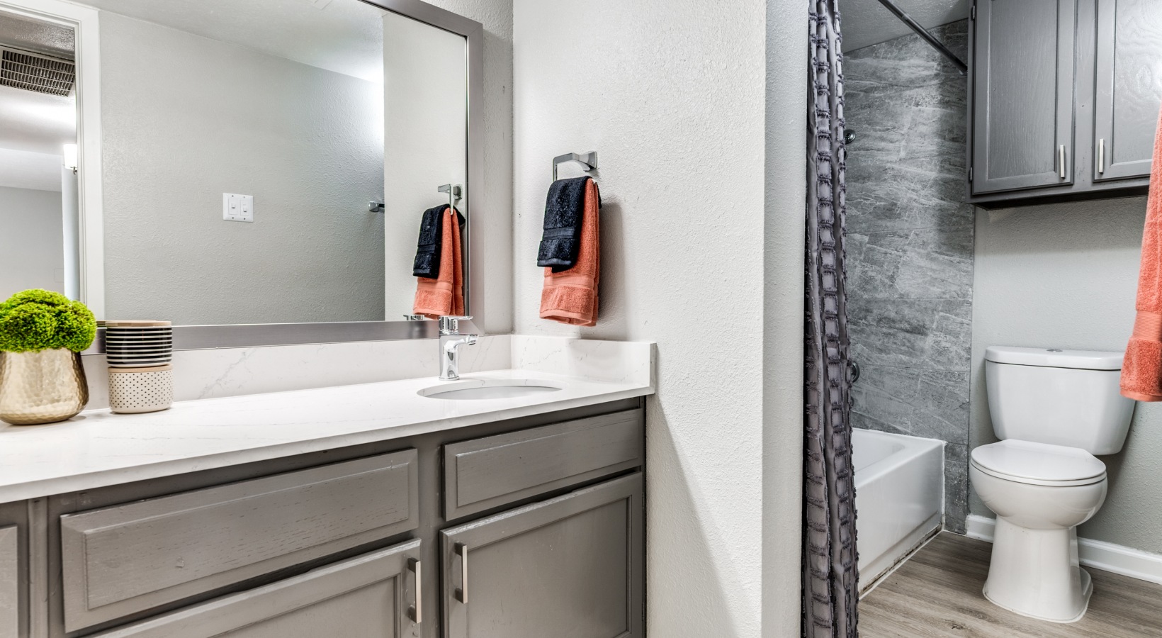 a bathroom with a gray vanity and white cabinets at The  Kace