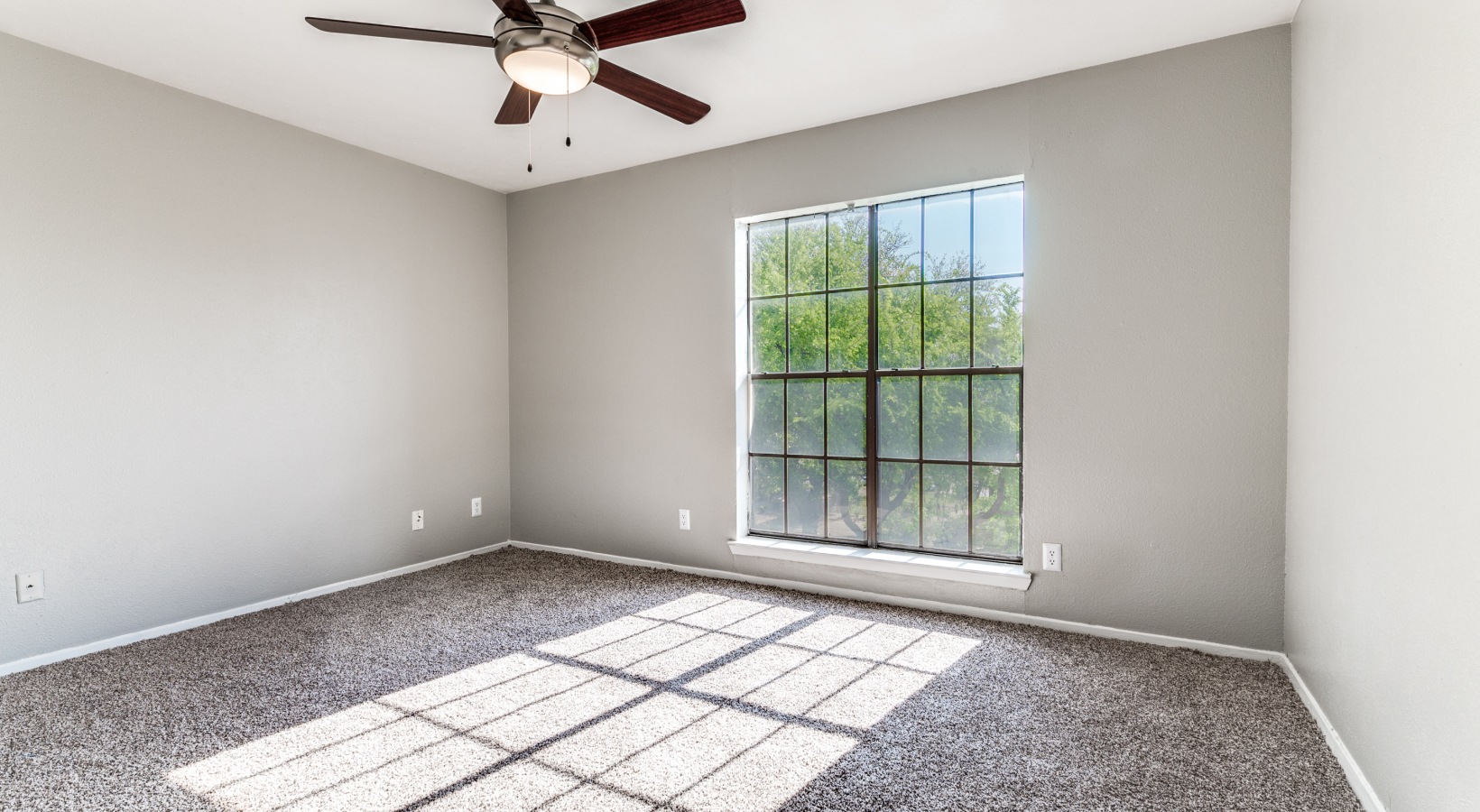 empty room with ceiling fan and carpet at The  Kace
