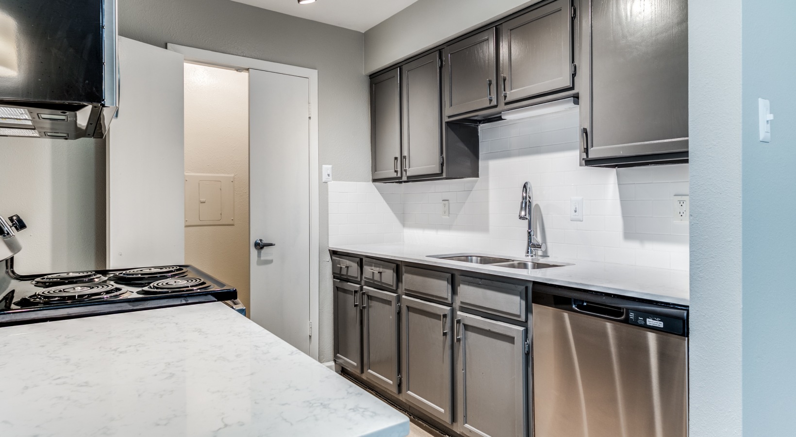 a kitchen with stainless steel appliances and gray cabinets at The  Kace