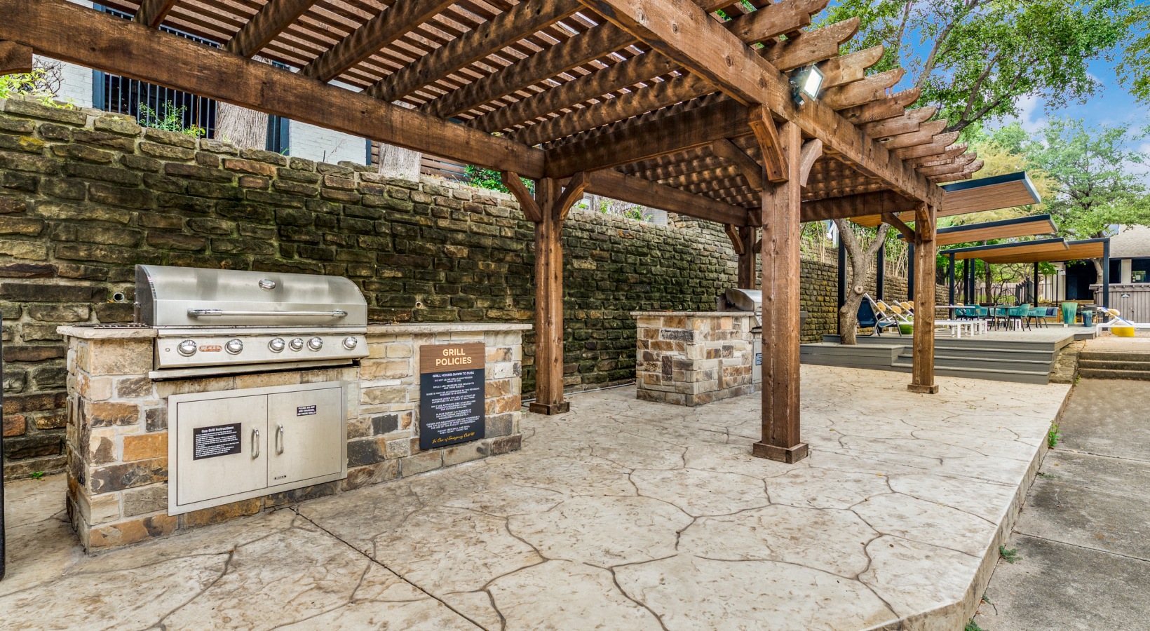 a covered outdoor kitchen with a grill and a pergola at The  Kace