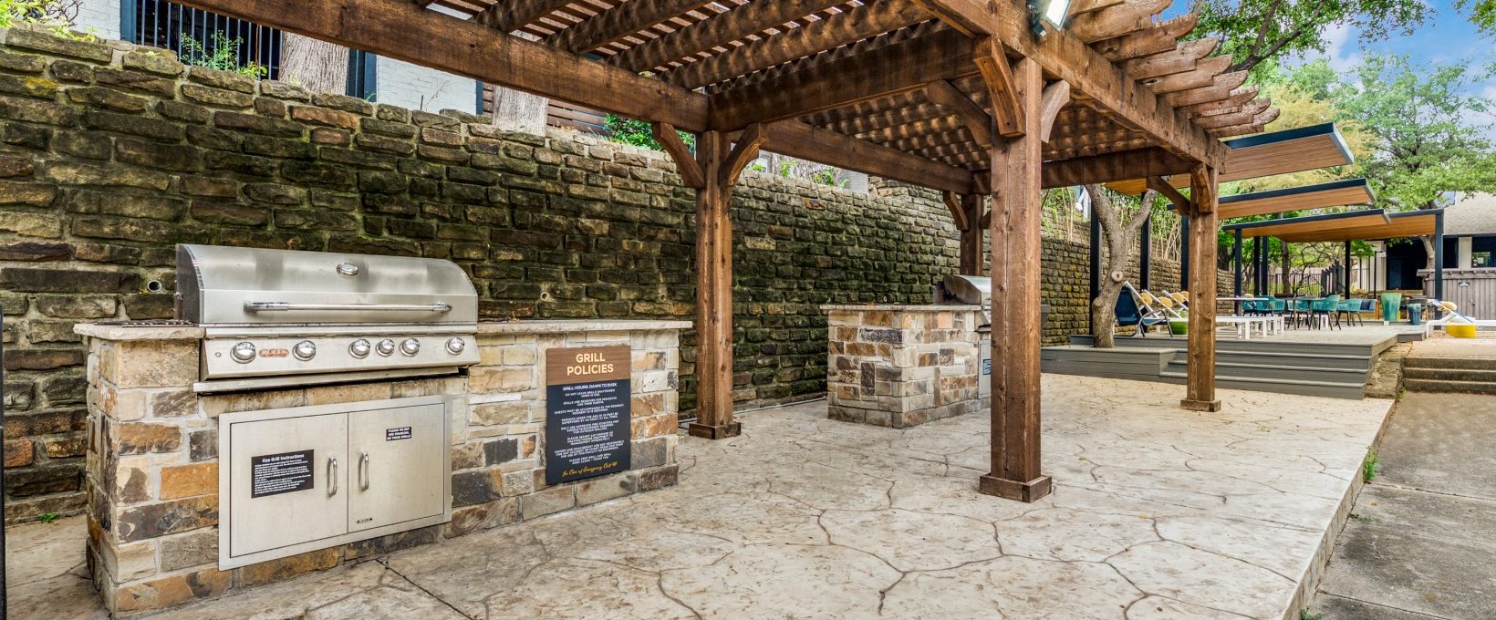 a covered outdoor kitchen with a grill and a pergola at The  Kace