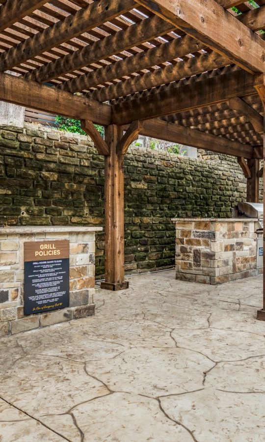 a covered outdoor kitchen with a grill and a pergola at The  Kace