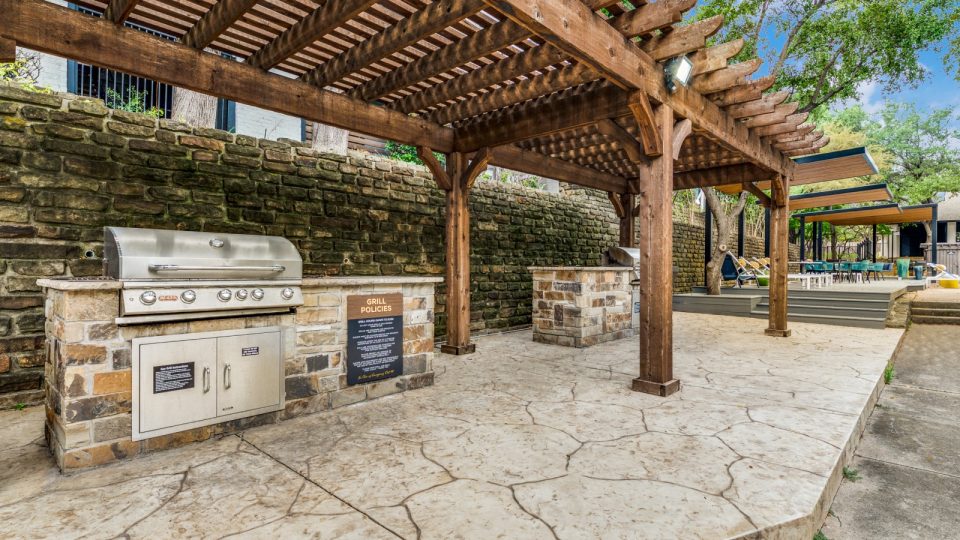 a covered outdoor kitchen with a grill and a pergola at The  Kace